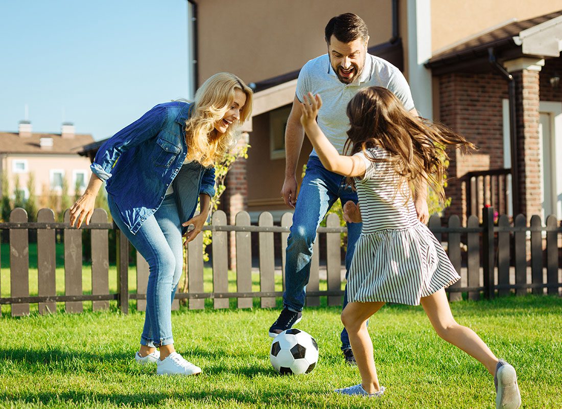 Personal Insurance - Happy Family and Child Playing Soccer Outside of Their House